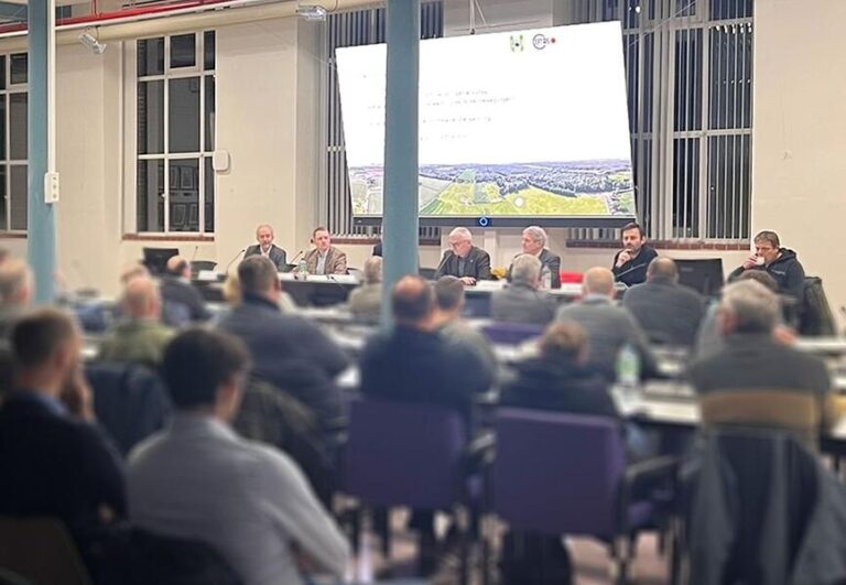 Menschen im Veranstaltungsraum, vorne ein Panel